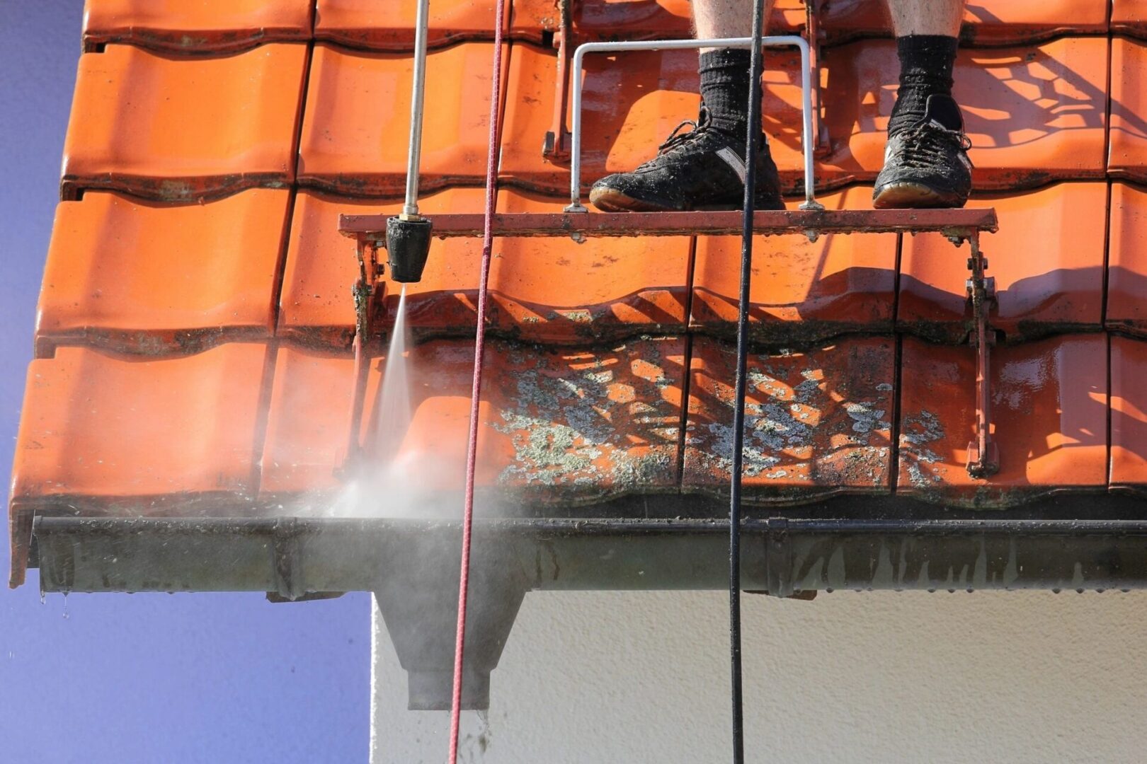 A person is cleaning the roof of a house.