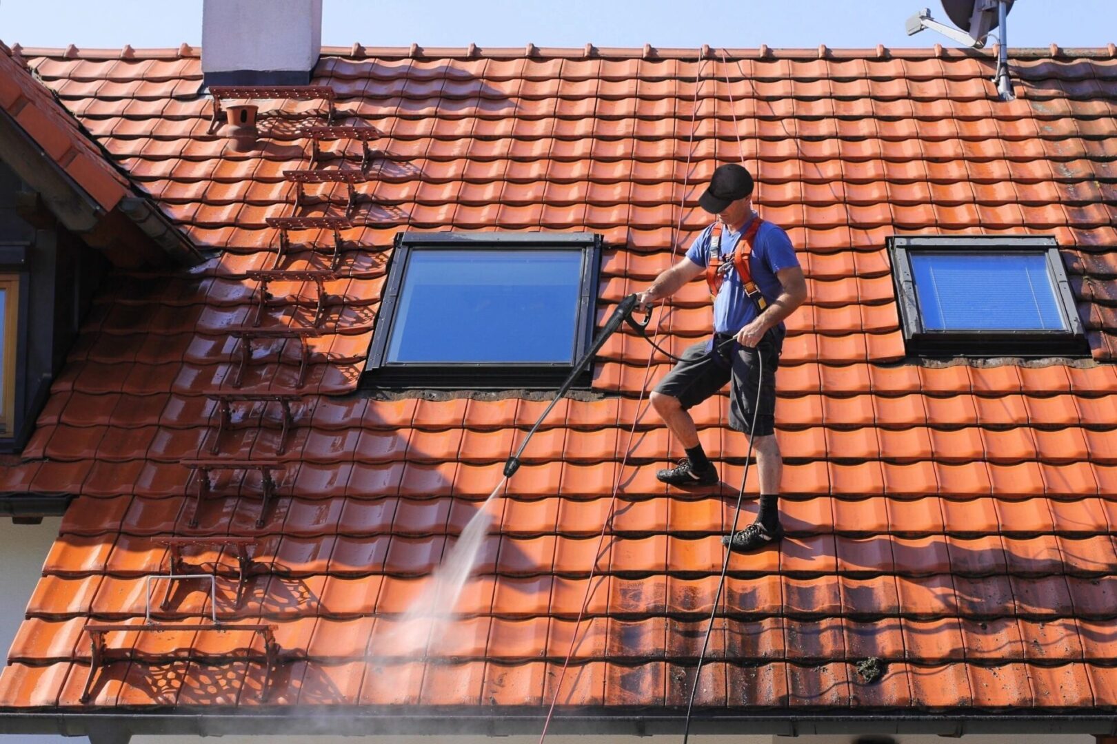 A man is cleaning the roof of his house