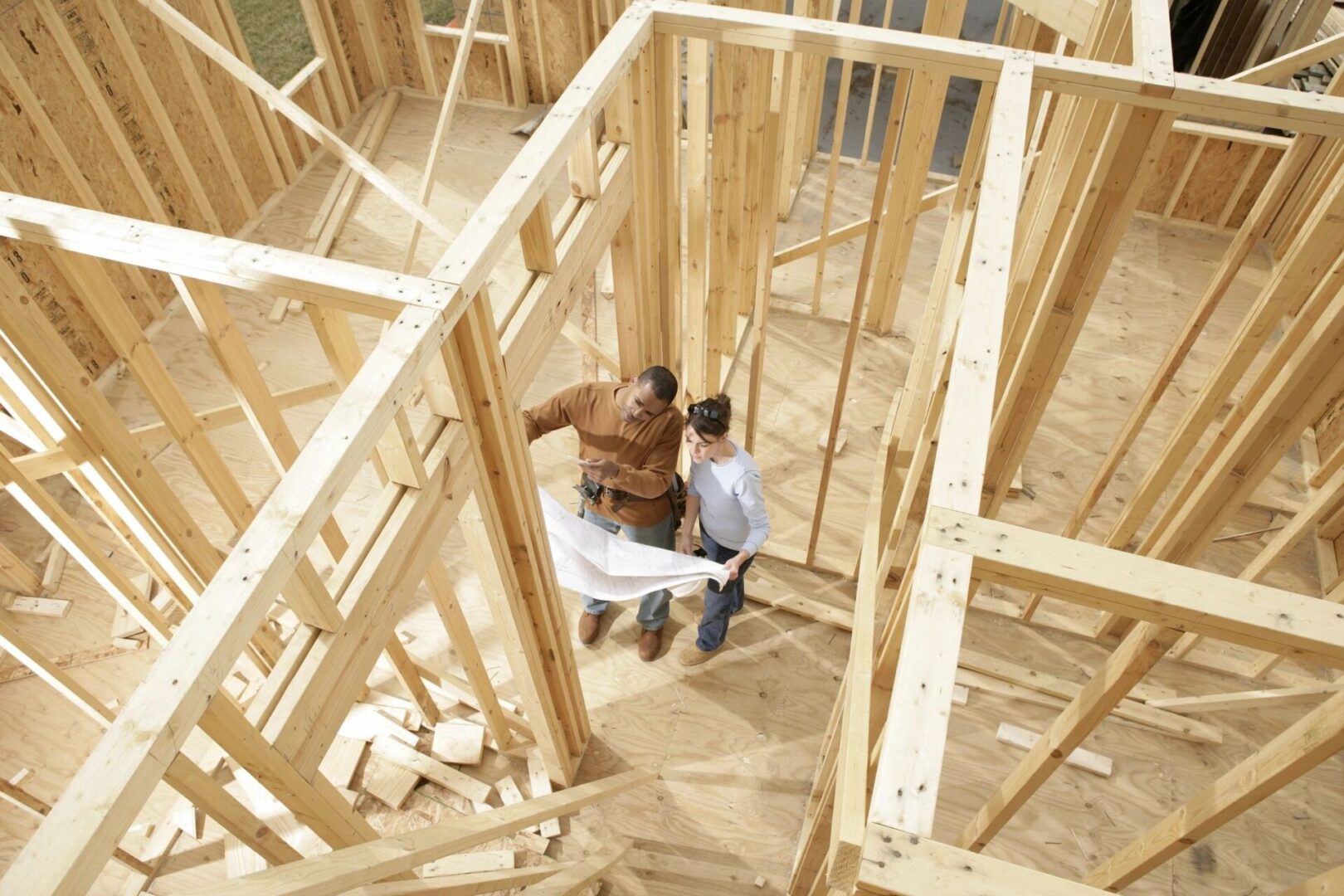 A man and woman in construction site with wood framing.