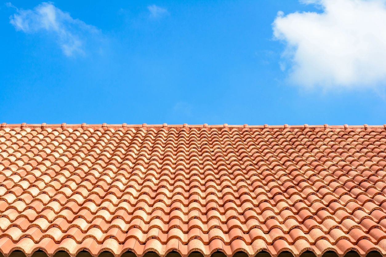 A roof with red tiles on it and blue sky in the background.